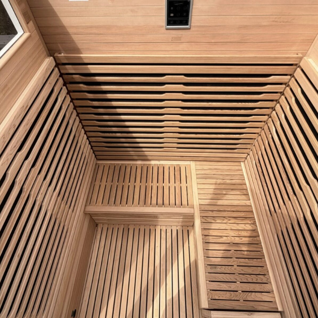 Top-down view inside the Bella Deluxe 3 cedar sauna showing benches, control panel and floor